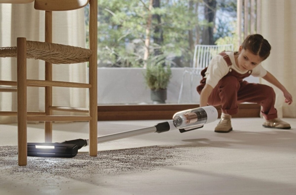 Dievčatko vysáva neporiadok pod stoličkou s vysávačom Electrolux.