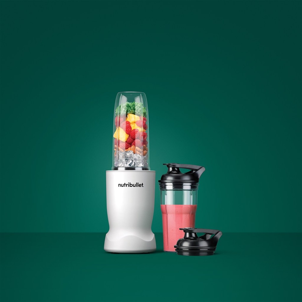 Stolný mixér Nutribullet TURBO 1000 NBT1006MW biely Mixér NutriBullet čierny s prenosným kelímkom s ružovým smoothie na zelenom pozadí.