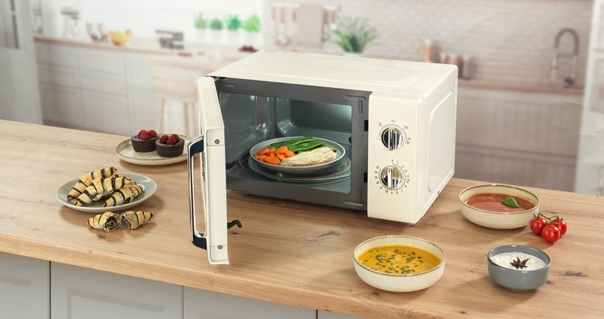 Mikrovlnná rúra Gorenje Retro MO20E1HRL béžová Retro mikrovlnka Gorenje MO20E1HRL je položená na kuchynskej linke. Dvierka má pootvorené a okolo nej sú naskladané potraviny.