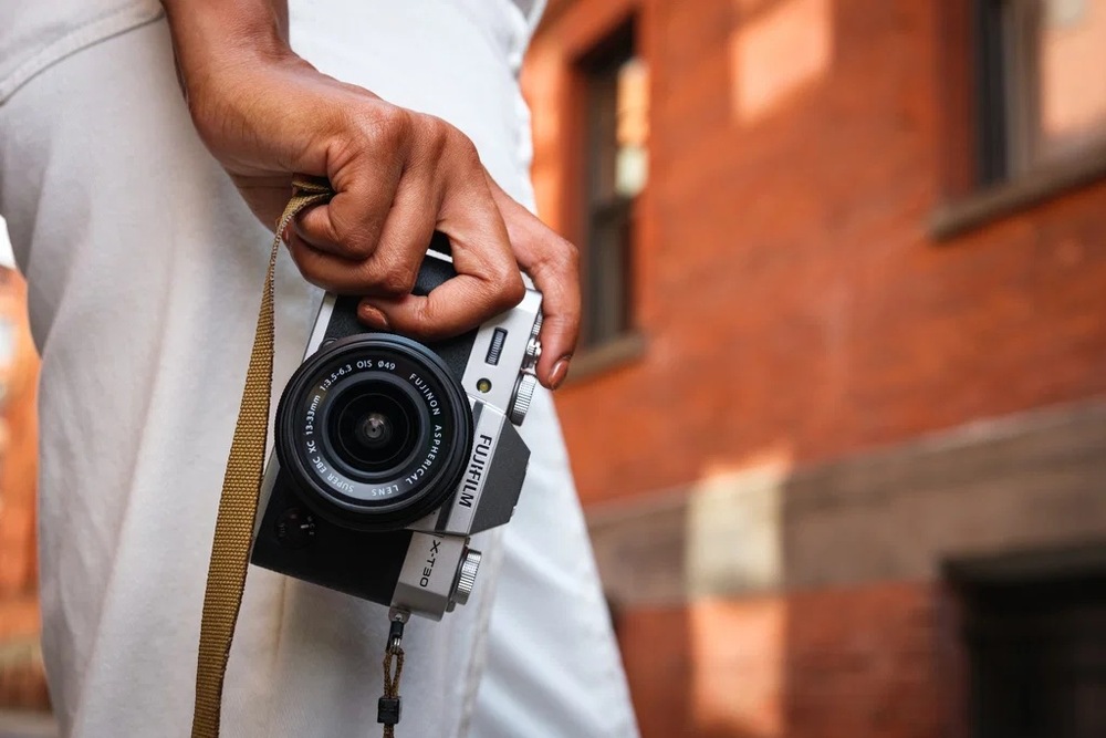 Digitálny fotoaparát Fujifilm X-T30 III, telo čierny Detal idúce osoby s kompaktným fotoaparátom Fujifilm X-T30 III v ruke