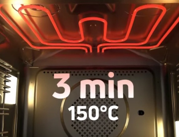 Rozohriate výhrevné teleso vo vnútri rúry. Cez mriežku ventilátora je nápis 3 minúty a 150 °C.