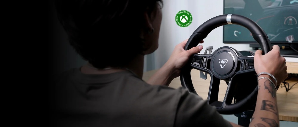 Záber na používateľa držiaceho v rukách volant Turtle Beach VelocityOne Race KD3. Na pozadí vidíme monitor zobrazujúci scénu zo závodnej hry.