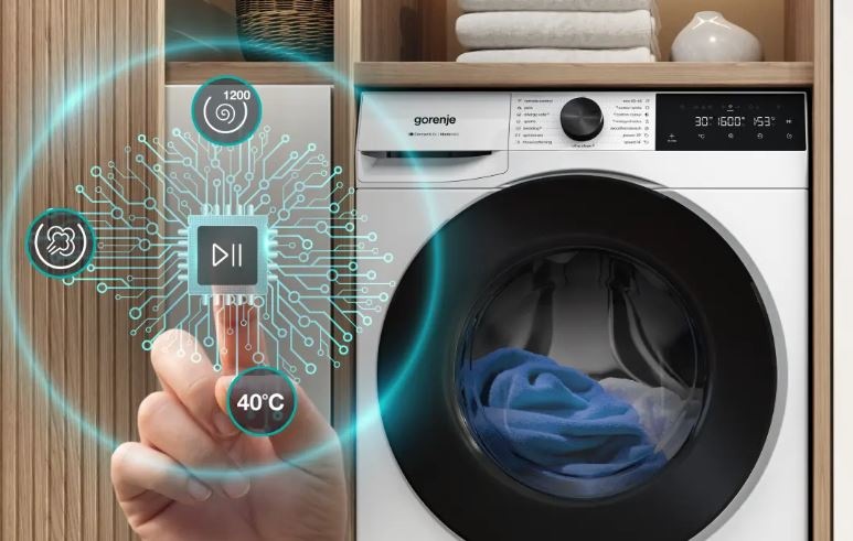 zobrazenie funkcie AdapTech na práčke gorenje. V kolieskach sú vidieť otáčky, stupne alebo použitie pary. Práčka je zabudovaná do drevenej steny. Nad ňou sú uteráky
