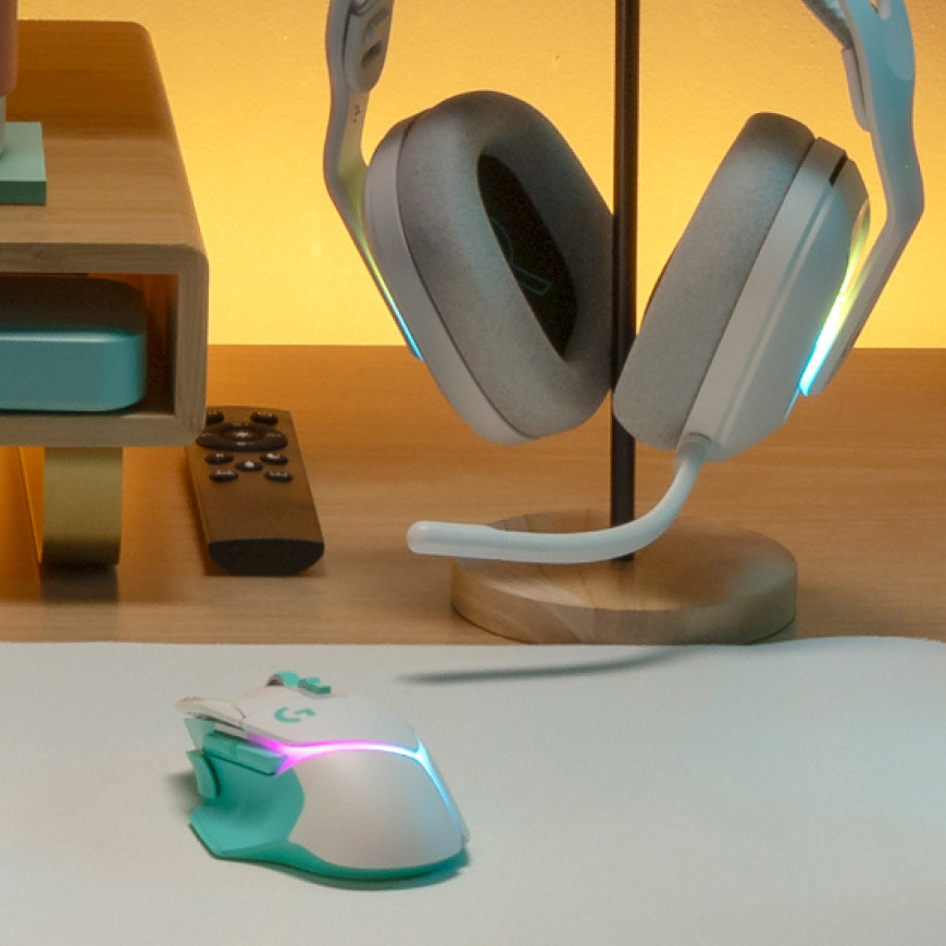 Myš Logitech G502 X Plus položená na stole vedľa herného headsetu na stojane