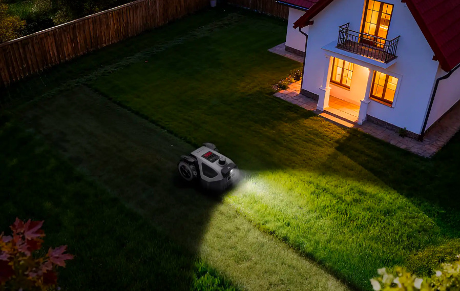 Robotická kosačka Anthbot M5 LiDAR so zapnutým osvetlením pri večernej prevádzke