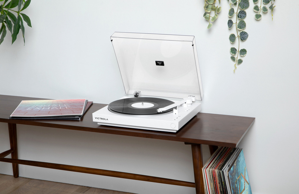 Gramofón Victrola VPT-800 Automatic biely Victrola VPT-800 Automatic pri počúvaní vinylu v obývacej izbe, otvorený kryt a dosky uložené pod stolíkom