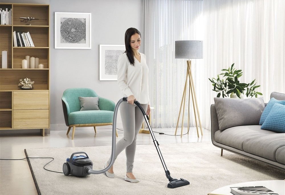 Žena vysáva vysávačom Electrolux ECGC21-2CB CompactGo Cyclonic koberec v obývačke.