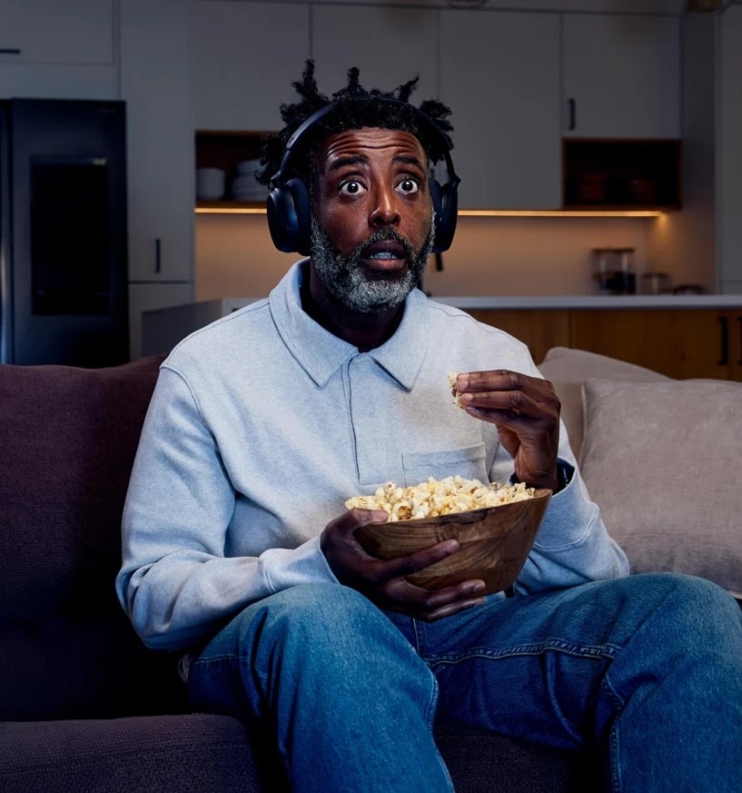 Slúchadlá Sennheiser RS275 TV čierna Muž s misou popcornu je ponorený do sledovania filmu so slúchadlami Sennheiser RS275 TV