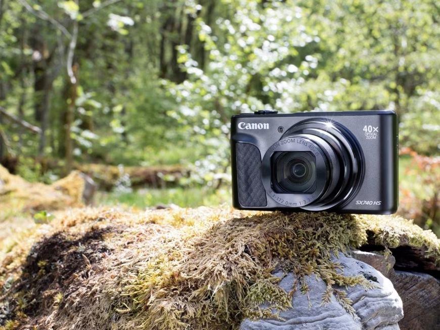 Digitálny fotoaparát Canon PowerShot SX740 HS, TRAVEL KIT II čierny Prenosný kompaktný foťák PowerShot SX740 HS LITE EDITION položený v lese