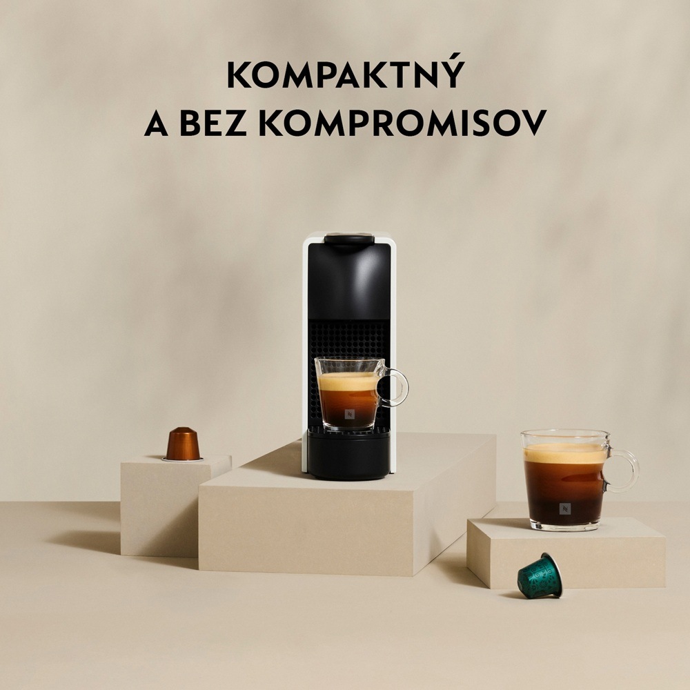 Kapsulový kávovar Krups Nespresso Essenza mini XN110AF0 krémový Kapsľový kávovar Essenza Mini na kuchynskej doske so šálkami kávy a kapsulami