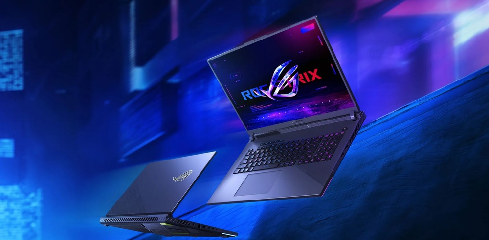 Dva herné notebooky sú vystavené na modrom a fialovom futuristickom pozadí. Jeden je otvorený a na jeho žiarivom displeji je nápis ROG STRIX.