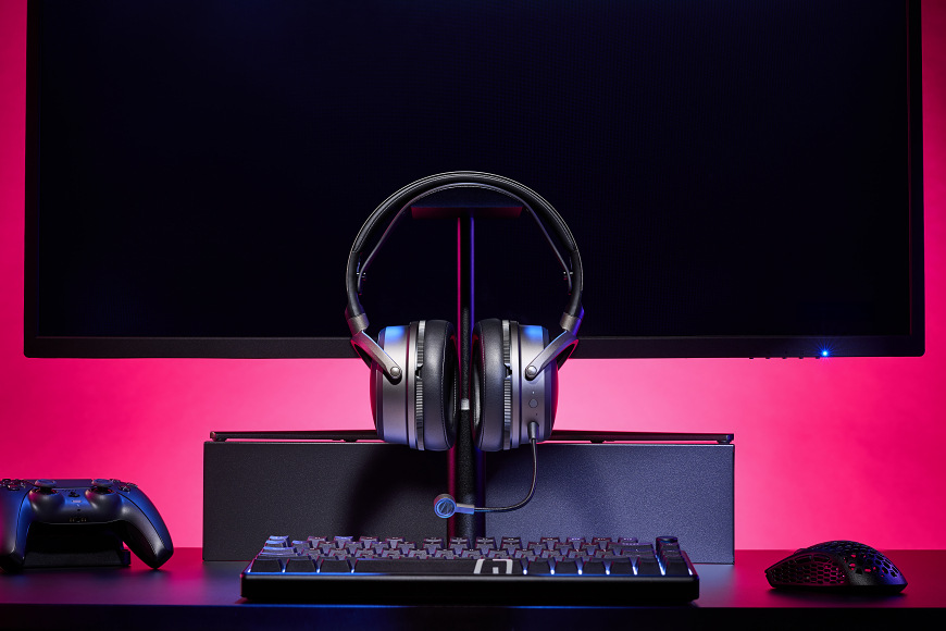 Headset Audeze Maxwell 2 PlayStation sivý Headset na stojane pred monitorom s herným príslušenstvom
