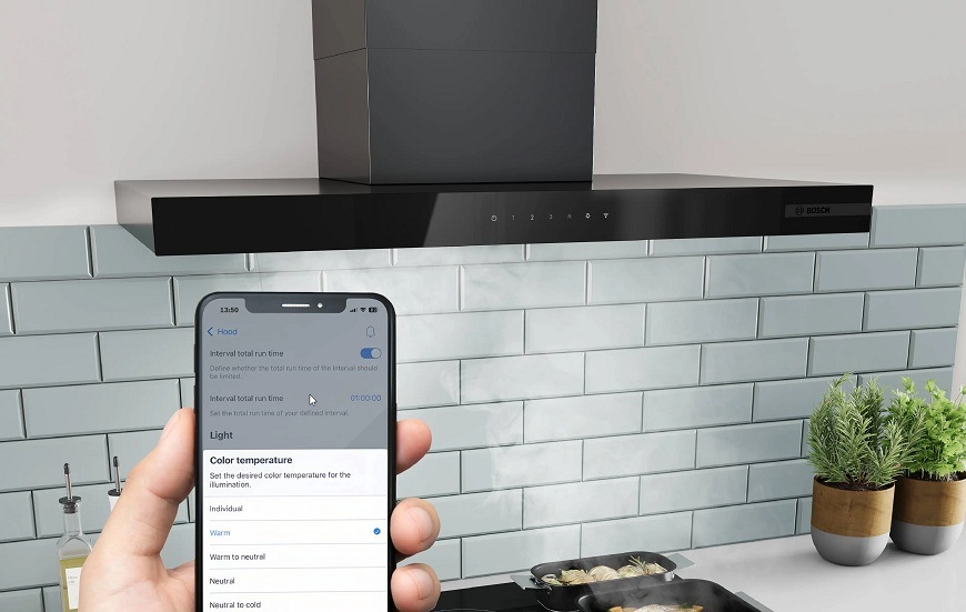Náhľad na mobilný telefón s aplikáciou Home Connect, v pozadí varná doska a odsávač pár