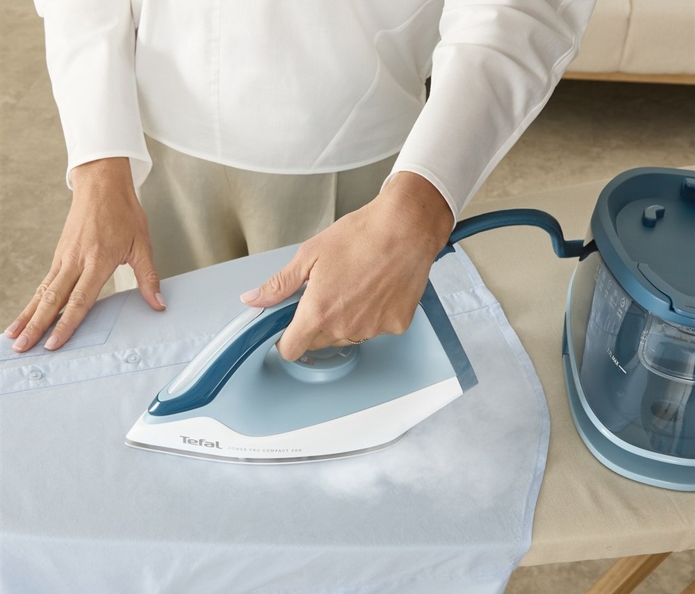 Žehliaci systém Tefal SV6212E0 Power Pro Compact 200 biely/modrý žena používa parný generátor Tefal SV6212E0 Power Pro Compact 200 na vyžehlenie košele.