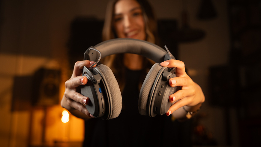 Headset ENDORFY VIRO Infra Wireless Alt Grey sivý Užívateľka držiaca headset ENDORFY VIRO Infra Wireless Alt Grey a ukazujúca jeho ovládacie prvky a konektory