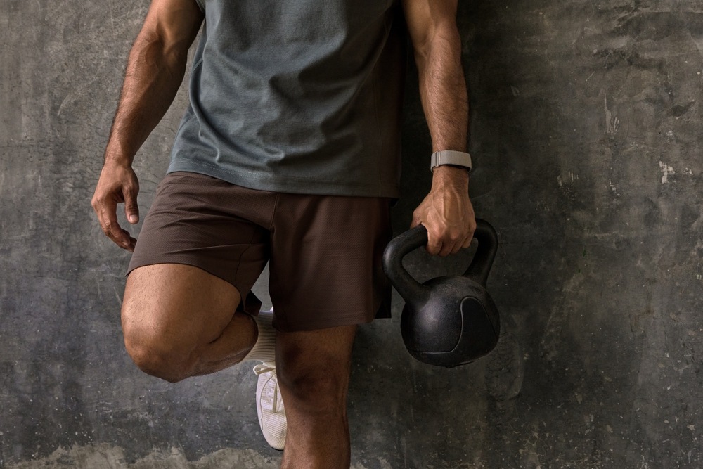 Fitness náramok Garmin CIRQA™ Smart Band S/M ružový Detail muža zvierajúceho kettlebell v ruke s fitness náramkom Garmin CIRQA Smart Band