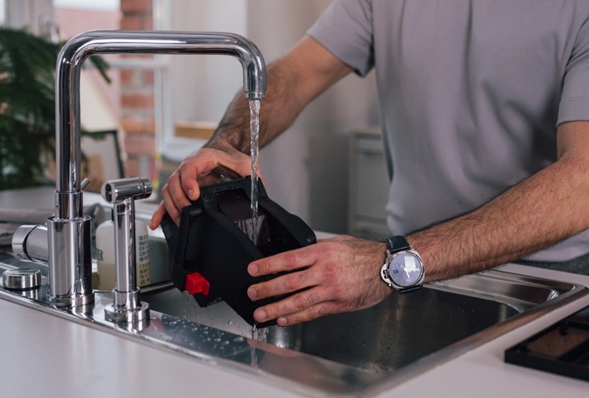 Muž oplachujúca sparovaciu jednotku v dreze.