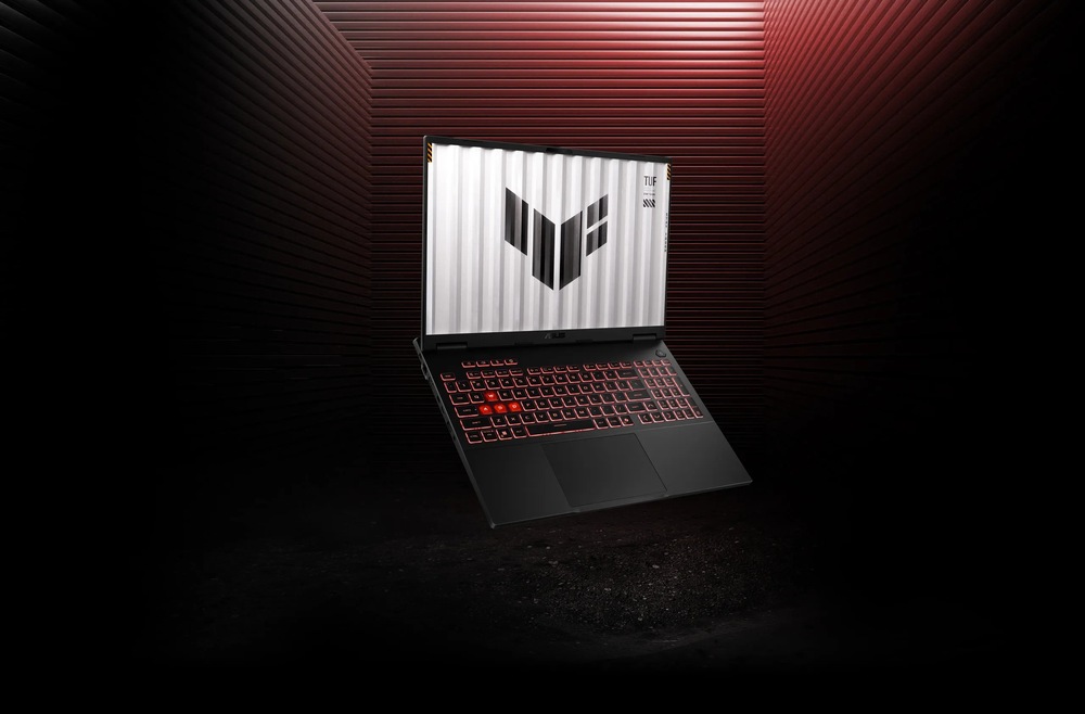 Elegantný herný notebook s červeno podsvietenou klávesnicou sa vznáša v tmavom industriálnom prostredí s červeným ambientným osvetlením.