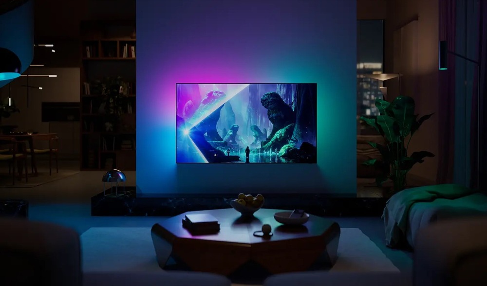 Televízor Philips 65OLED801 Obrázok zachytáva technológiu Ambilight, kedy LED osvetlenie reaguje na dianie na obrazovke farebným premietaním na stenu za televízorom.