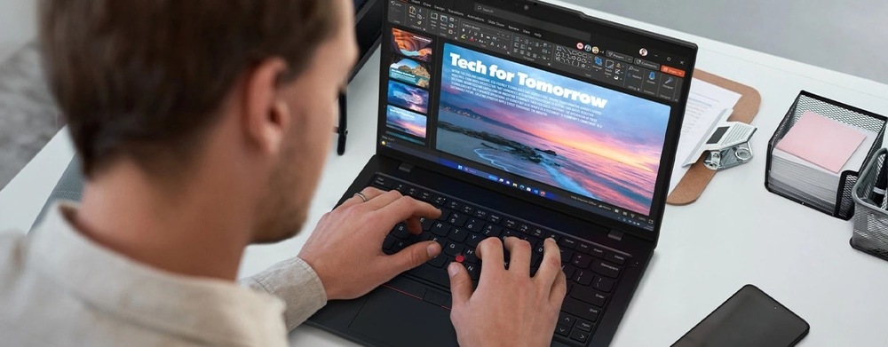 Notebook Lenovo ThinkPad L14 Gen 6 čierny Osoba píše na notebooku, na ktorom je zobrazená prezentácia s názvom „Technológia pre zajtrajšok“. Na jasnej snímke je zachytený západ slnka nad pokojným oceánom.