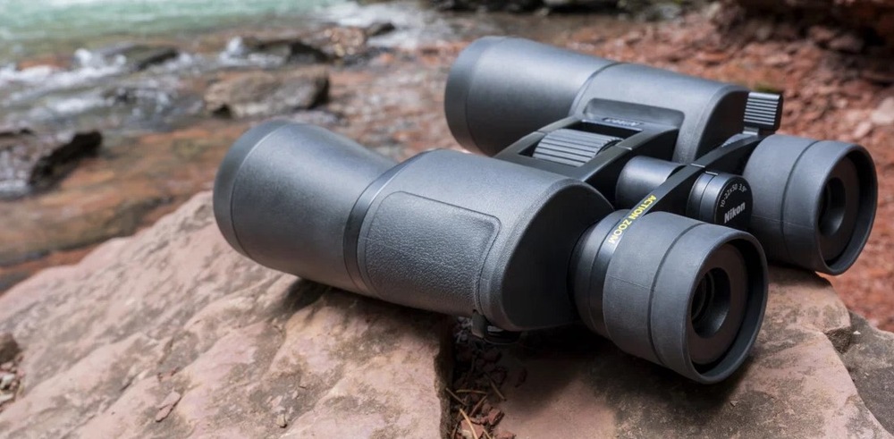Ďalekohľad Nikon Action 12×50 čierny Ďalekohľad Nikon Action 12×50 je položený na kamenistom brehu rieky.