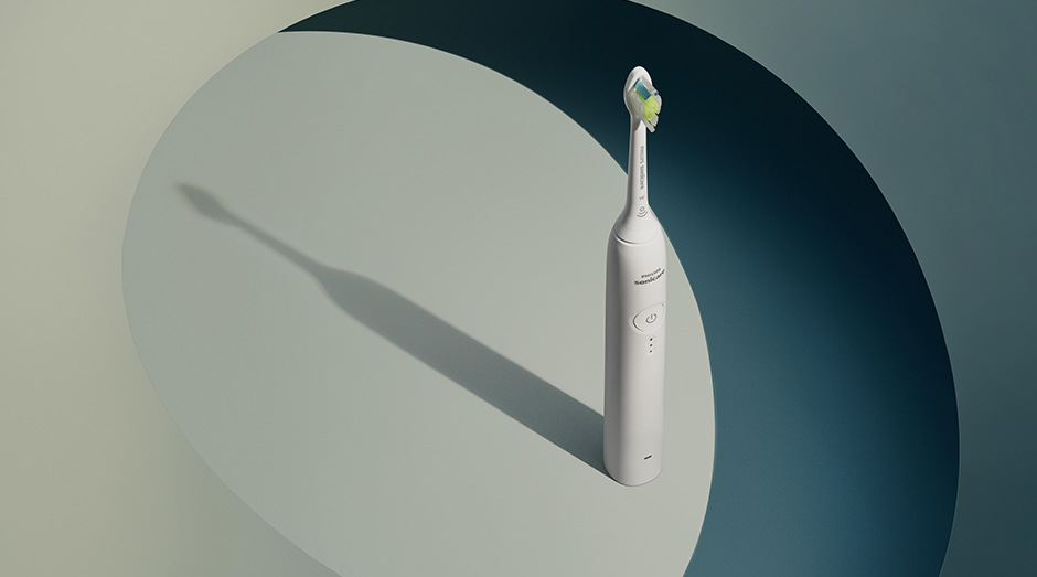 Zubná kefka Philips Sonicare 3100 HX4033/21 biela Stojaca kefka Philips HX4033/21 Sonicare 3100 a za ňou tieň