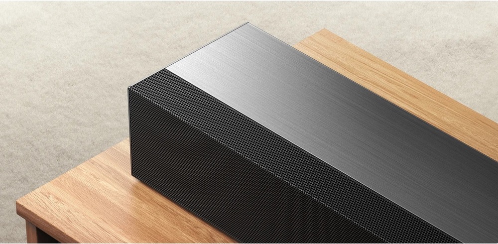 Soundbar Xiaomi PRO 2.1 ch čierny Detail kovovej hornej plochy soundbaru Xiaomi PRO 2.1 ch položeného na drevenom TV stolíku