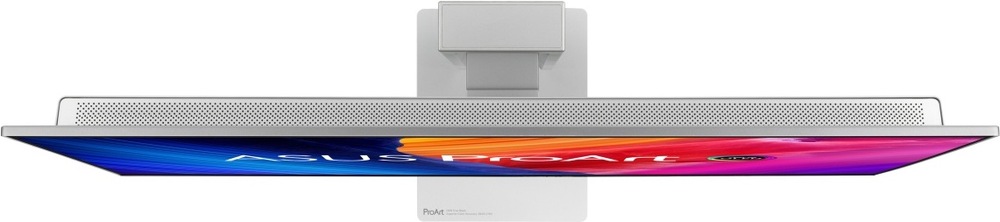 Na obrázku je monitor Asus ProArt OLED PA27UCDMR 27" z horného pohľadu. Je vidieť veľmi tenké telo displeja, strieborná zadná časť s dlhou perforovanou vetracou mriežkou a uprostred uchytenia k stojanu. Spodný okraj obrazovky zobrazuje farebnú grafiku ASUS ProArt. Snímok zdôrazňuje štíhly profil.