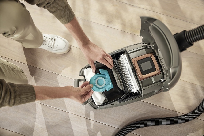 Vrecká pre vysávače Miele TU XL HyClean Pure (8 ks) Muž vymieňa vo vysávači Miele sáčok