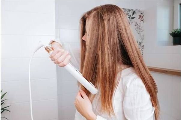 Žehlička na vlasy Concept GLAM Style VZ2110 biela Žena si v kúpeľni vyrovnáva dlhé vlasy pomocou žehličky Concept VZ2110 Glam Style