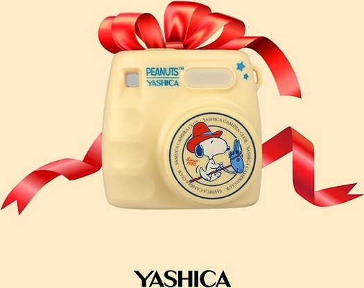 Digitálny fotoaparát Yashica x Peanuts Mini Digital Camera béžový Kompaktný fotoaparát Yashica x Peanuts Mini Digital Camera s červenou darčekovou stuhou na ilustračnej produktovej fotografii