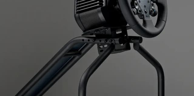 Pretekársky kokpit Next Level Racing RC ESSENTIAL Simulator Cockpit čierny Detailný záber čierneho volantu závodného simulátora a robustného kovového rámu na šedom pozadí, ktorý navodzuje dojem elegantného, technického a vysoko výkonného zariadenia.