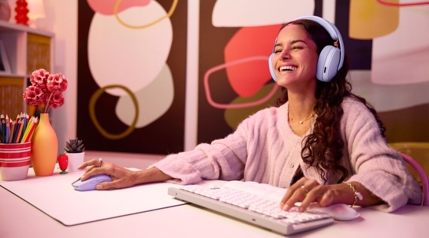 Hráčka pri počítači hrá hru so svetlým herným headsetom Logitech G325 LIGHTSPEED Wireless na hlave