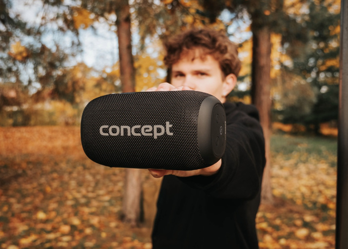 Mladý muž drží prenosný reproduktor Concept SoundJoy BR5020 v jesennom parku