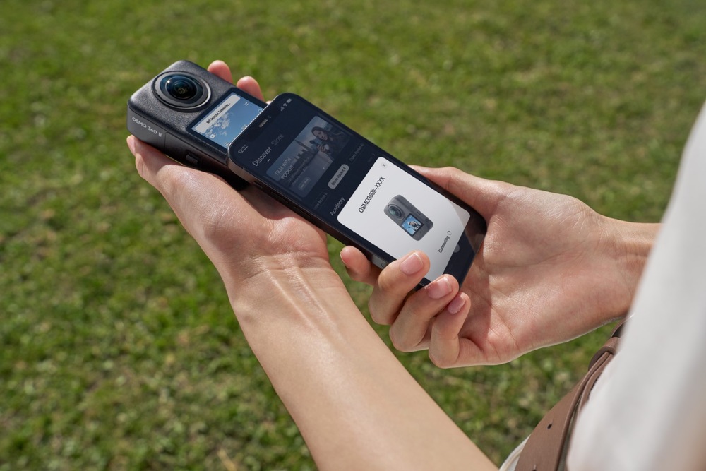 Outdoorová kamera DJI Osmo 360 II Standard Combo čierna Ruky držia kameru DJI Osmo 360 II vedľa smartfónu pri pripájaní k mobilnej aplikácii