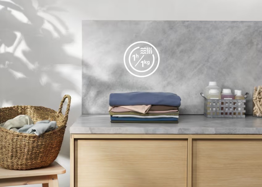 Práčka so sušičkou Electrolux EW5W468WE biela Hromádka bielizne na linke. Nad ňou symbol pre program 60Min Wash&Dry. Vľavo kôš s bielizňou.