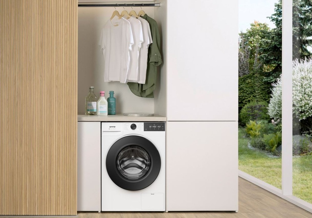 práčka Gorenje WG414A41 UltraClean zabudovaná do drevenej skriňovej steny, nad práčkou visi tričká na ramienku