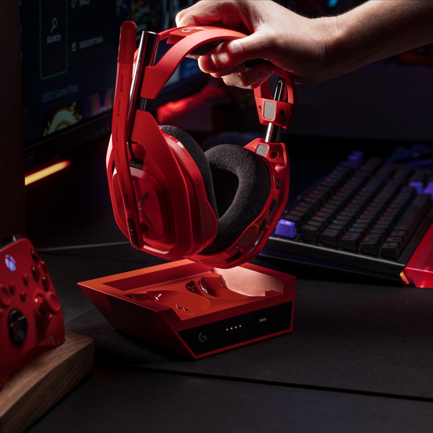 Headset Logitech G Astro A50 X Lightspeed Wireless + Base Station červený Ruka zdvíhajúca headset Logitech G A50 X LIGHTSPEED z nabíjacej základne na hernom stole