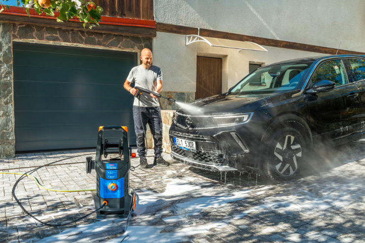 Vysokotlakový čistič Narex ECT 500 Užívateľ oplachuje prednú časť vozidla prúdom vody z Narex ECT 500 na dvore