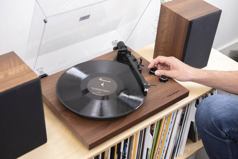 Gramofón Crosley C62 hnedý Detail gramofónu Crosley C62 pri prehrávaní vinylovej dosky a ovládaní hlasitosti