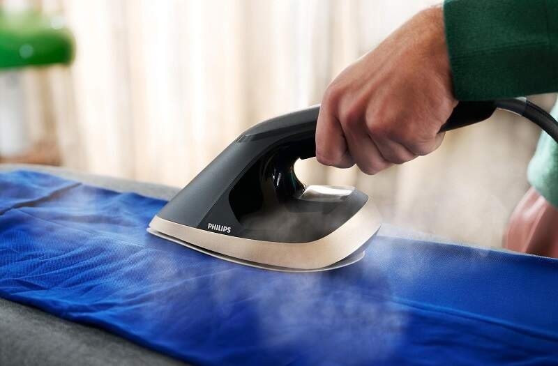 Muž naparuje nohavice žehličkou Philips AIS8540/80 Series 8500″ width=