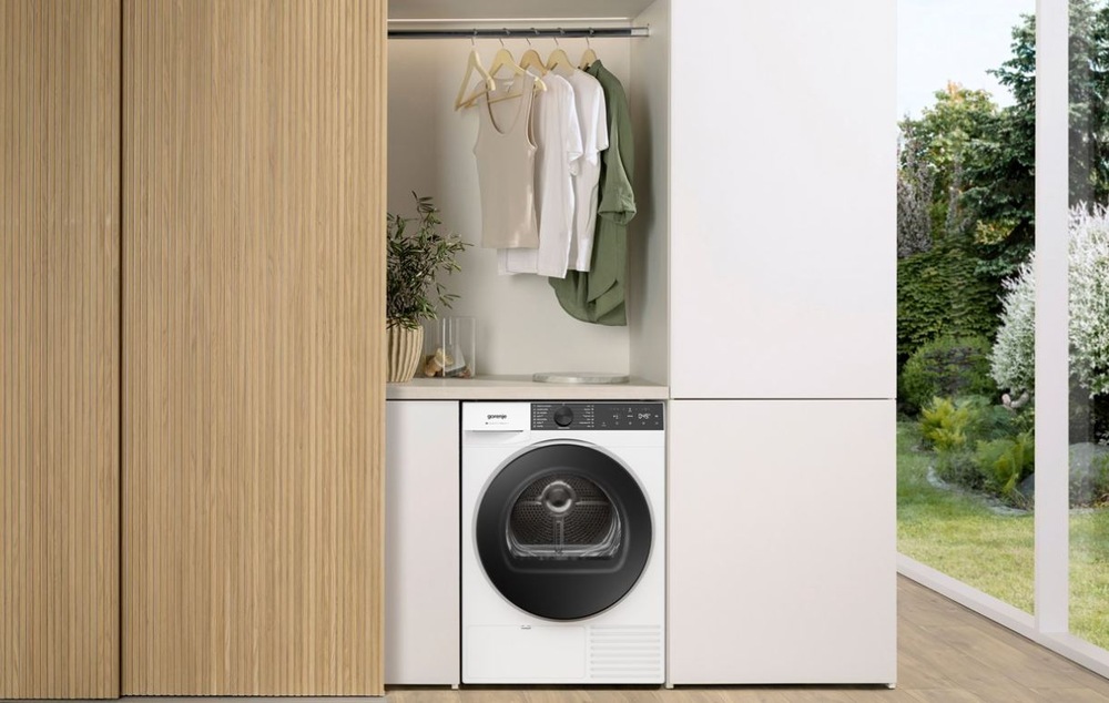 Sušička bielizne Gorenje G400 D48C NatureDry biela sušička Gorenje D48C NatureDry umiestnená vedľa šatníkovej skrine v drevenom dekore, na druhej strane je presklený vstup na záhradu. Nad sušičkou visi na ramienku tričká.