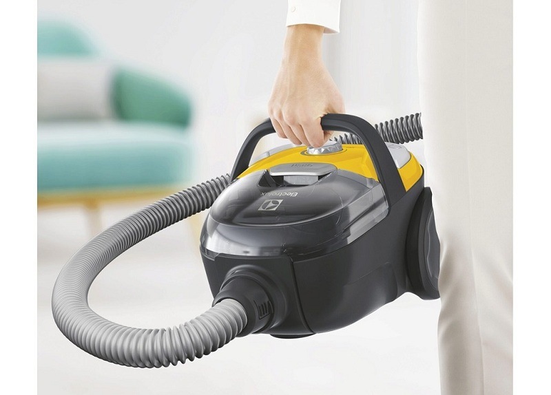 Podlahový vysávač Electrolux CompactGo Cyclonic ECGC21-2Y žltý Žena drží v ruke vysávač Electrolux ECGC21-2Y CompactGo Cyclonic.
