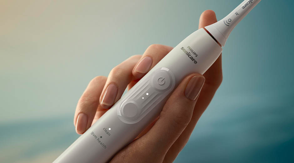 Zubná kefka Sonicare drží žena v ruke a idú vidieť tlačidlá na kefke