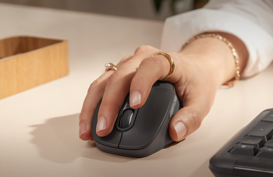 Ruka položená na myši Logitech Signature M850 L Wireless pri práci pri stole