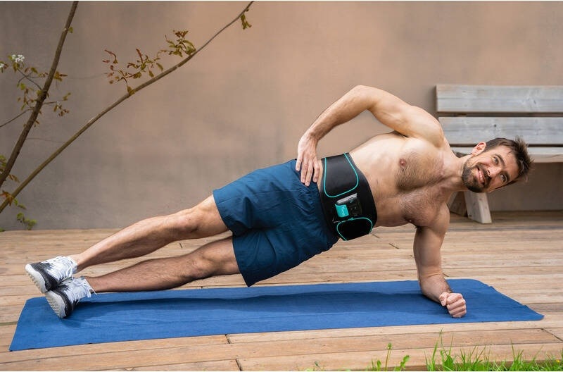 Elektrostimulátor Beurer Corefit I čierny Muž cvičí bočný plank na podložke s nasadeným brušným pásom Beurer Corefit I