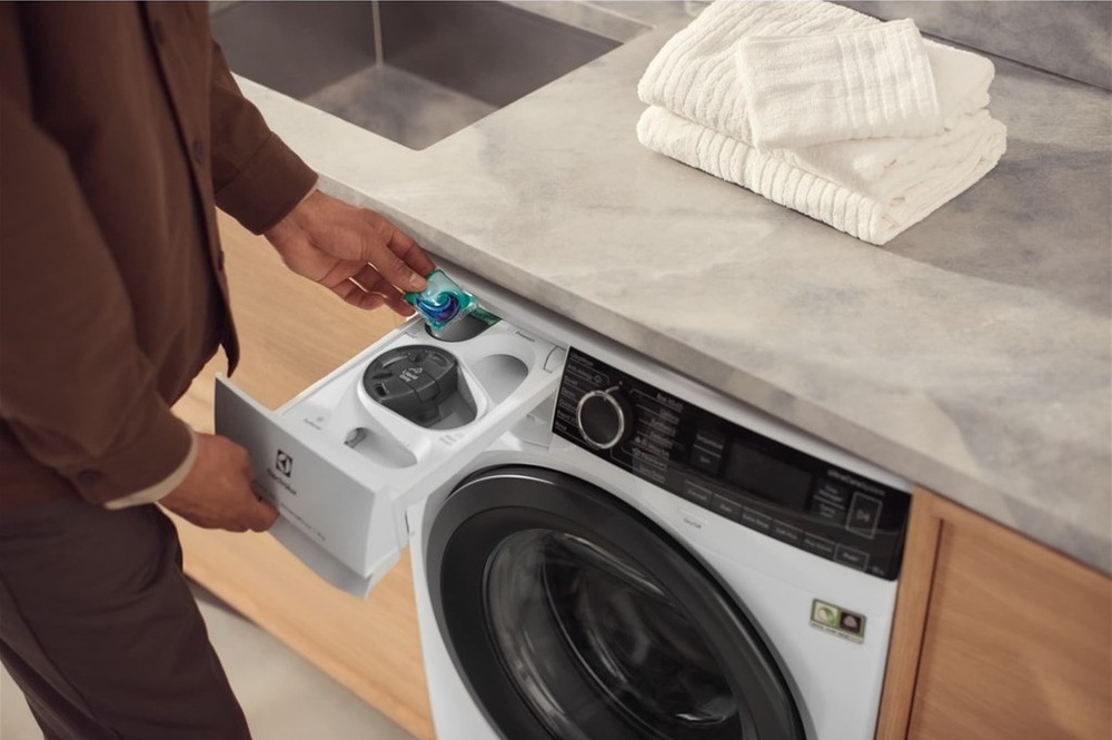 Práčka Electrolux UniversalDose UltraCare 800 EW8F3494SQC biela Práčka Electrolux s otvorenou zásuvkou UniversalDose. Muž do nej vkladá gélovú kapsulu.