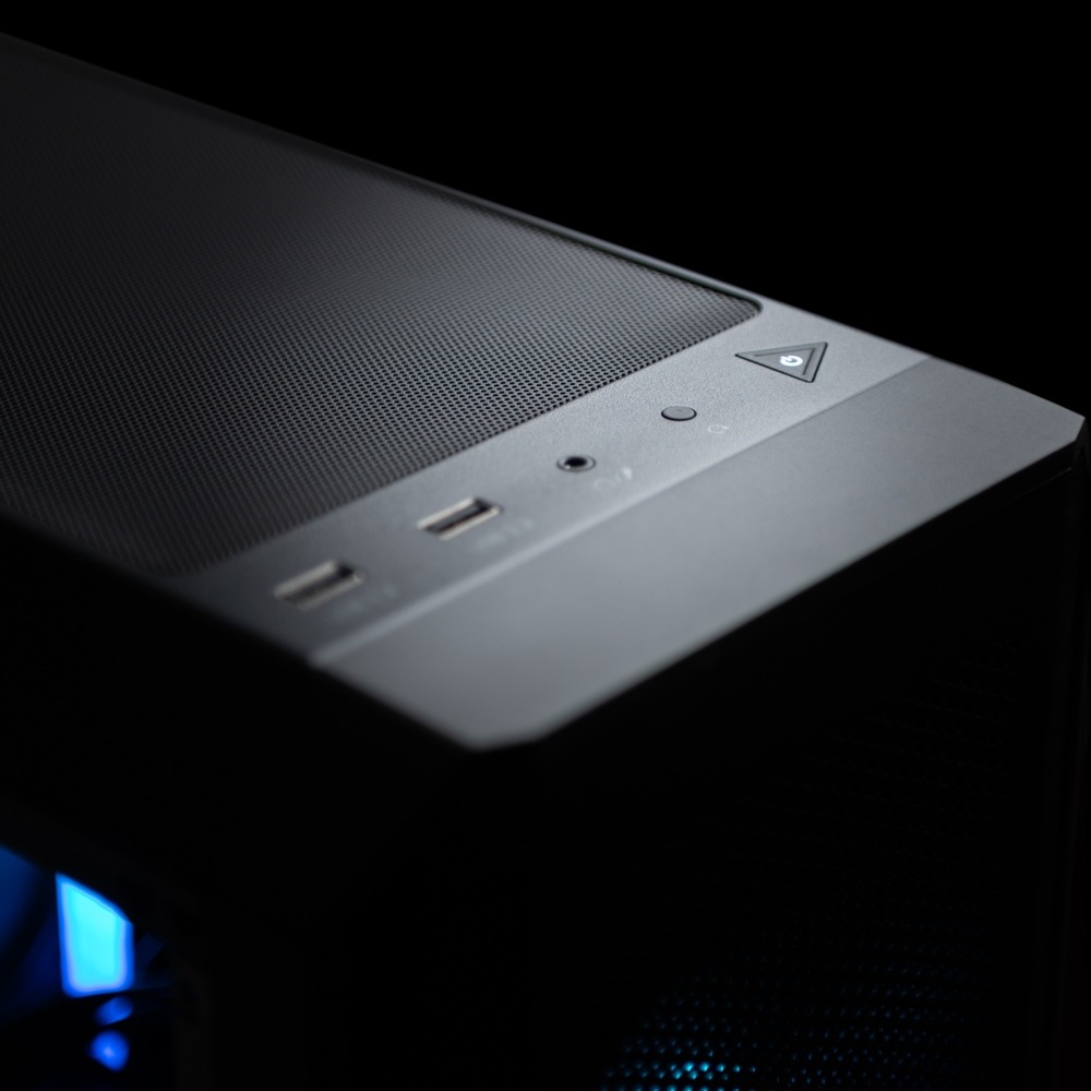 Herný počítač Lynx Challenger Ultra 5 čierny Detailný záber na elegantný horný panel počítačovej skrine za slabého osvetlenia s USB portami, konektorom pre slúchadlá a tlačidlom napájania s jemným modrým LED podsvietením.