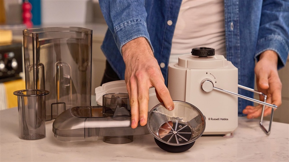 Ruka drží sitko odšťavovača Russell Hobbs