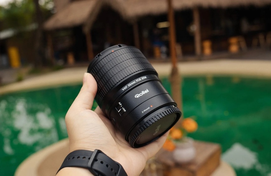 Objektív Rollei 35 mm AF f/1.8 (Nikon Z) čierny Objektív v dlani ilustruje kompaktnú veľkosť a nízku hmotnosť modelu Rollei 35 mm AF f/1.8